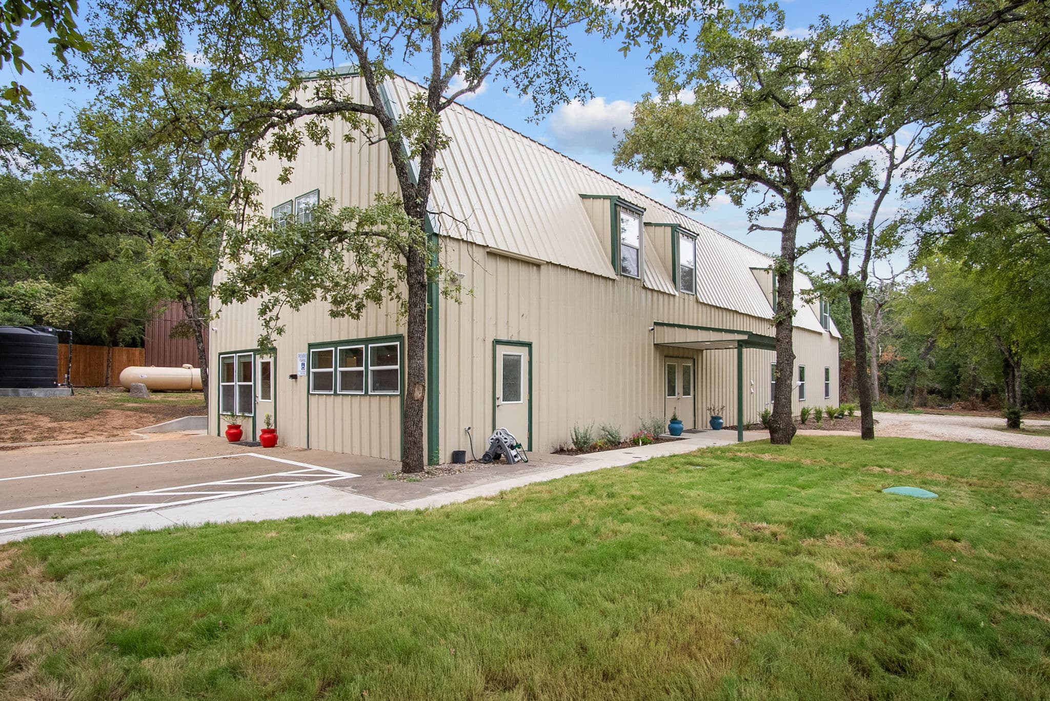 The barn residence and its lawn, shaded by oak trees